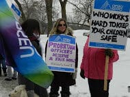 OPSEU members hold up signs and flags as they attend protest