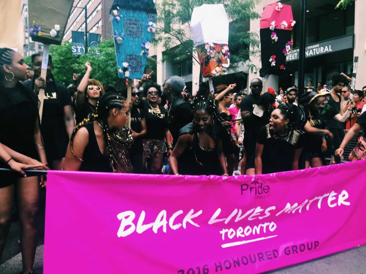 Large group of Black people and allies march with a "Black Lives Matter Toronto" banner during the Toronto Pride Parade.