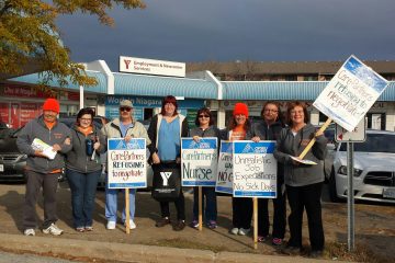 Group of striking CarePartners nurses holding signs picket YMCA job fair in St. Catharines
