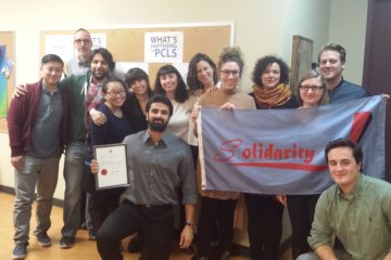 Summer caseworkers at Parkdale Community Legal Services hold a "Solidarity!" banner