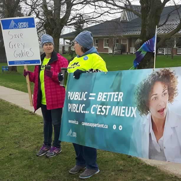OPSEU members hold picket signs and a "Public = Better" banner during a Save Grey Gables rally.