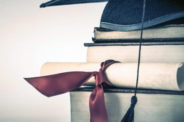 Grad cap and diploma atop textbooks