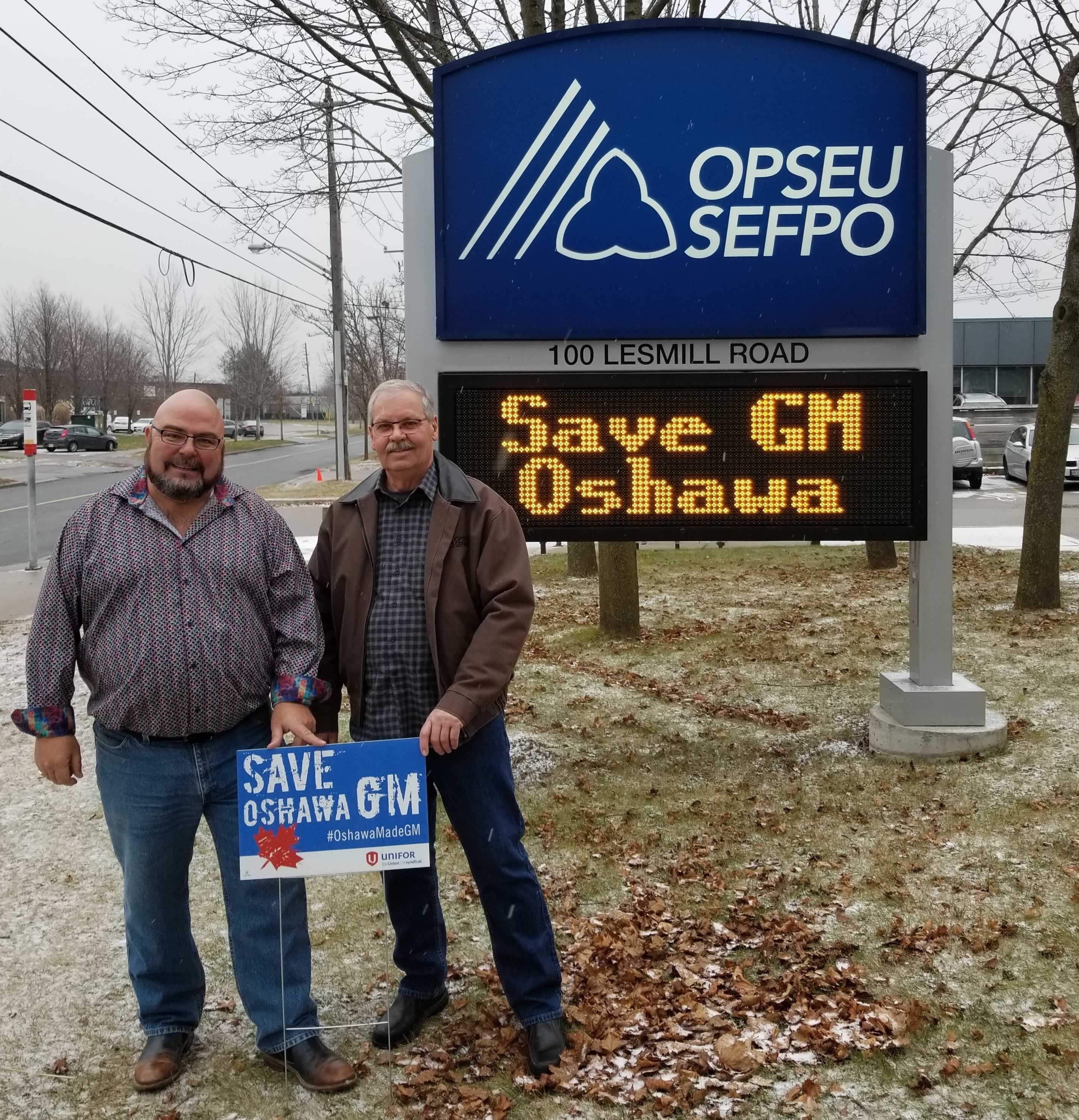 OPSEU President Warren (Smokey) Thomas and First Vice-President/Treasurer Eduardo (Eddy) Almeida pose outside OPSEU's head office with "Save Oshawa GM" signs