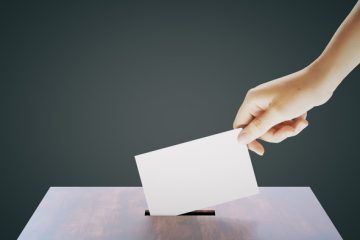 Hand placing ballot into box