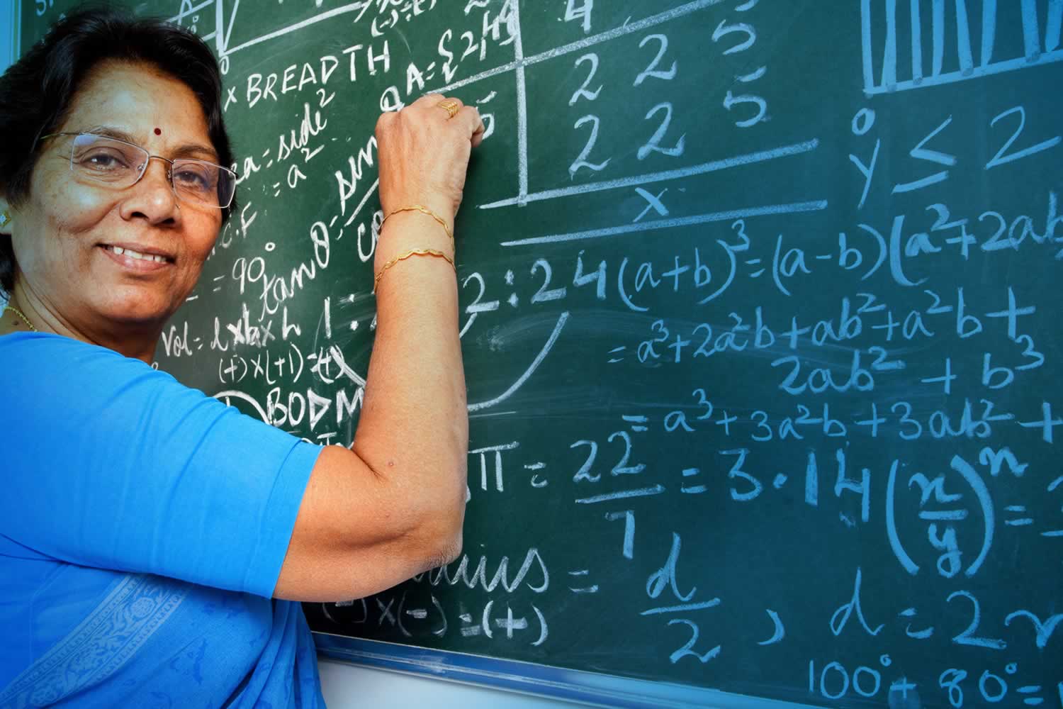 Woman standing at chalkboard writing equations