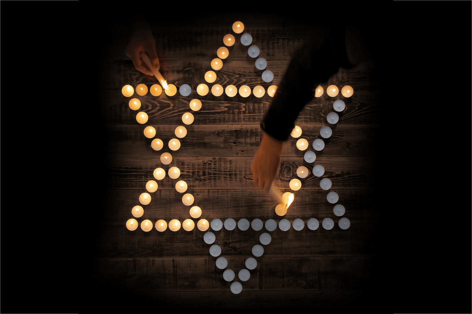 Two people lighting candles in the shape of the Jewish Star of David.