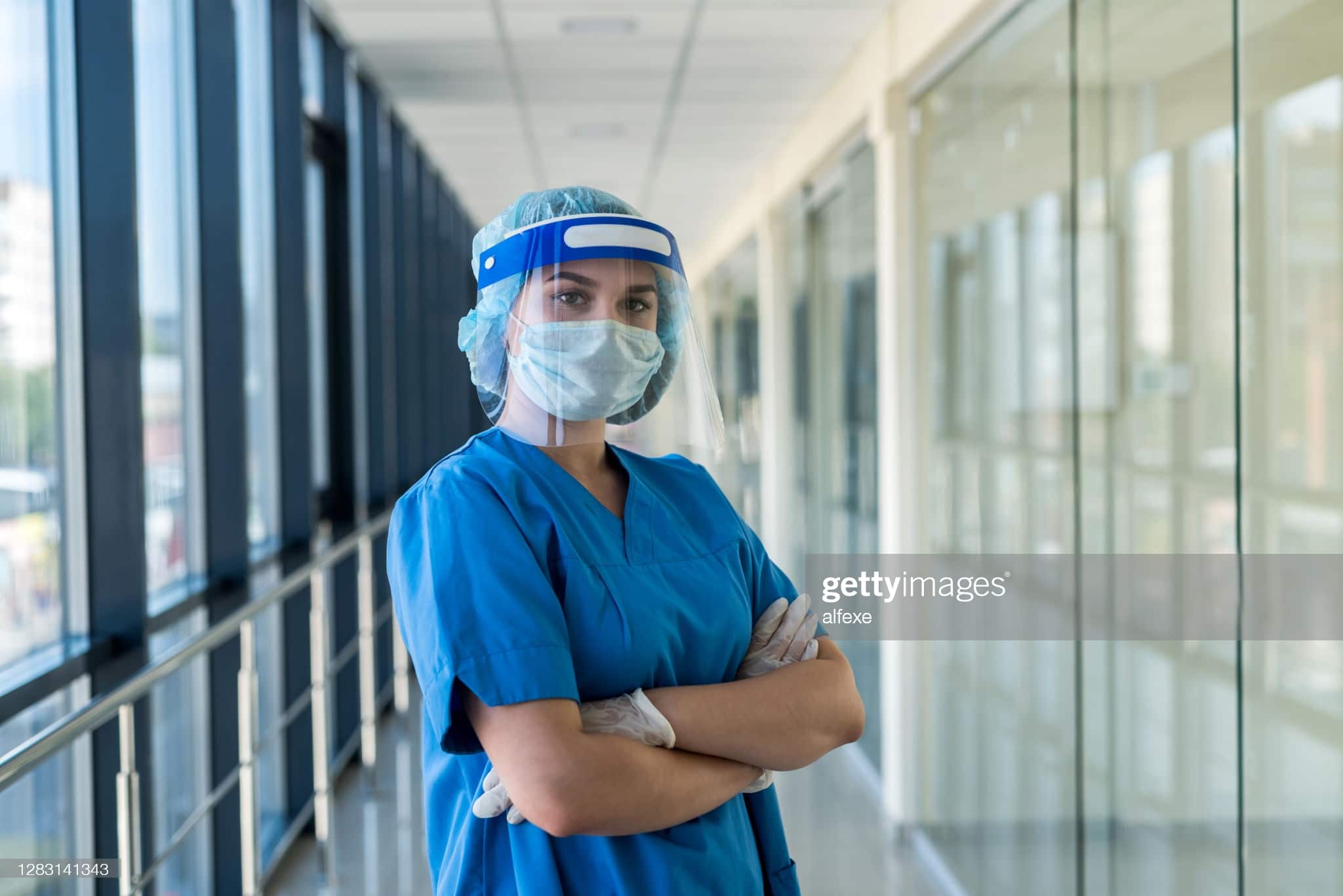 Healthcare worker in PPE crossing their arms